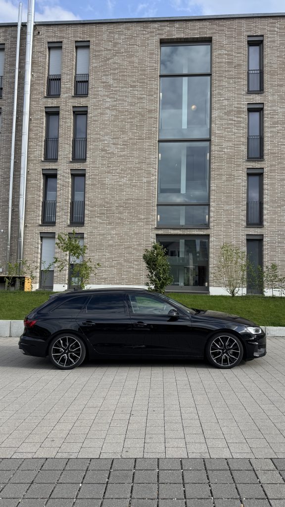 Schwarzer Audi A4 Avant seitlich geparkt vor modernem Gebäude – Beispielbild für Auto verkaufen und Fahrzeugankauf